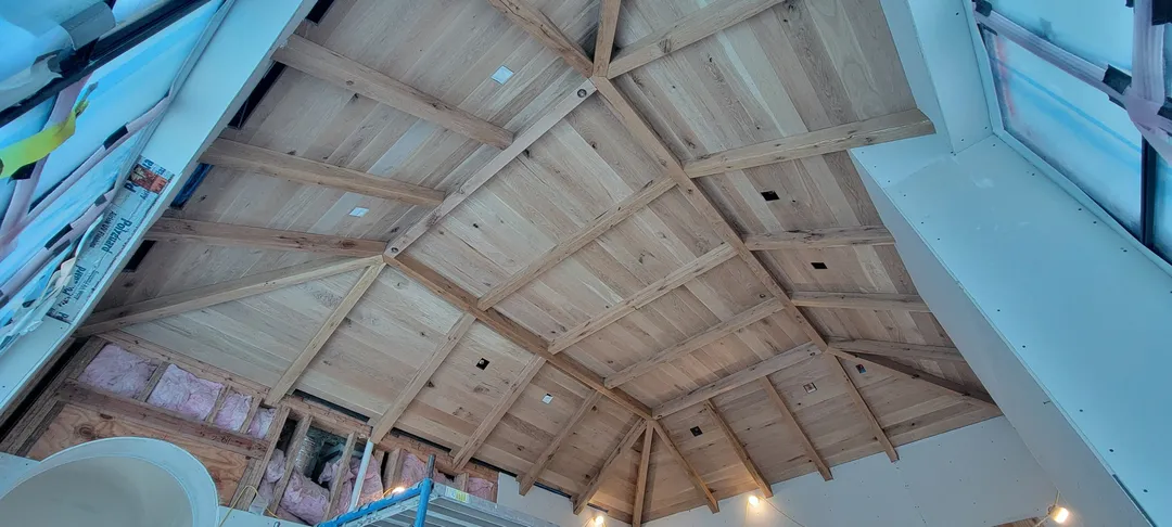 Finished custom wood ceiling with exposed beams, paneled bays, and integrated lighting.