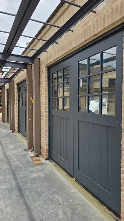 Dark paneled garage doors beneath a steel courtyard canopy at the Stoneridge project.