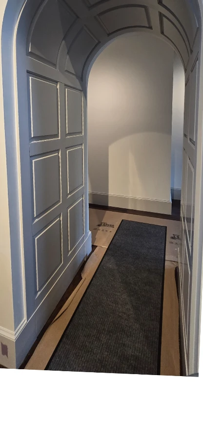 Curved paneled passage with its concealed arched door closed.