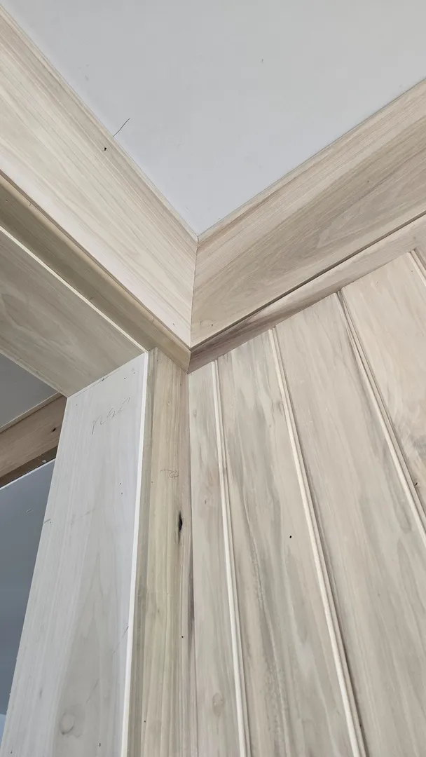 Close view of white oak wall panels meeting a shaped ceiling cove.