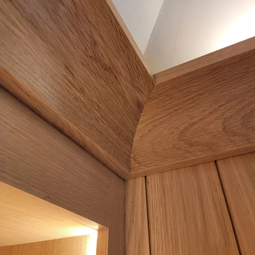 Precision mitered oak millwork wrapping an architectural corner beneath cove lighting.
