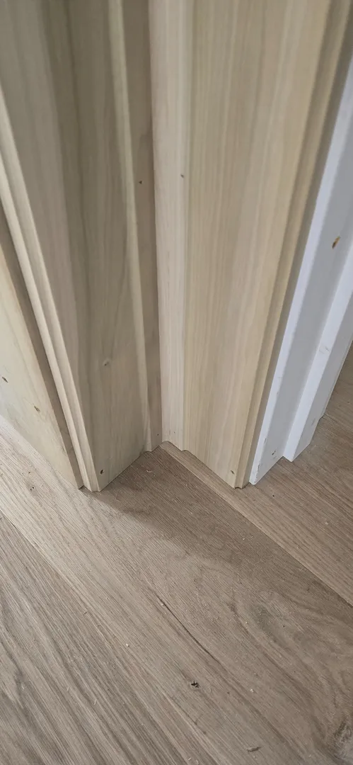 Close view of aligned white oak door casing and wall panel transitions.