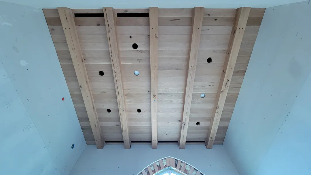 Centered view of a completed rectangular ceiling field divided by exposed wood beams.