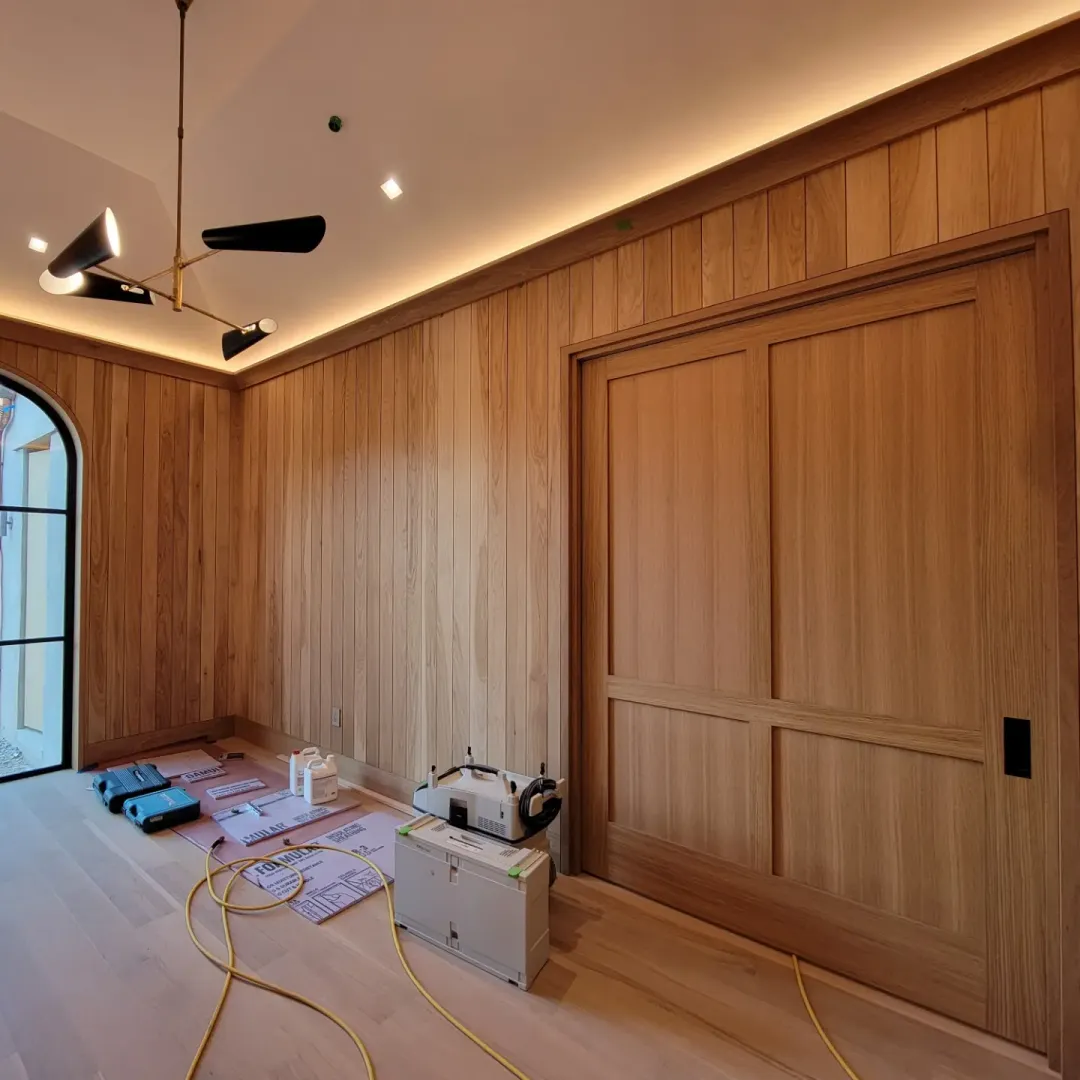 Oak-paneled room with an integrated concealed door and cove lighting.