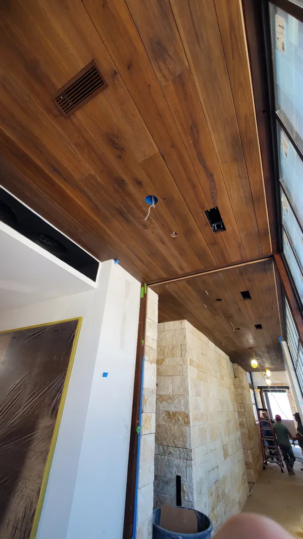 Long view of stained wood ceiling boards fitted between architectural walls and stonework.