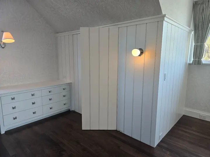 Painted casework installation with butterfly hardware beside a paneled bedroom enclosure at Stoneridge.