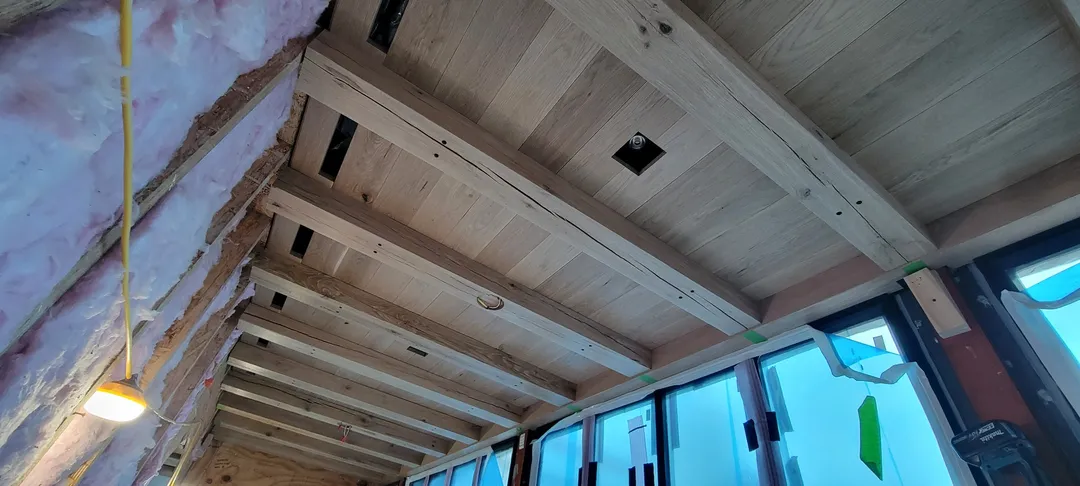 Custom wood ceiling installation in progress with exposed beams and coordinated openings.