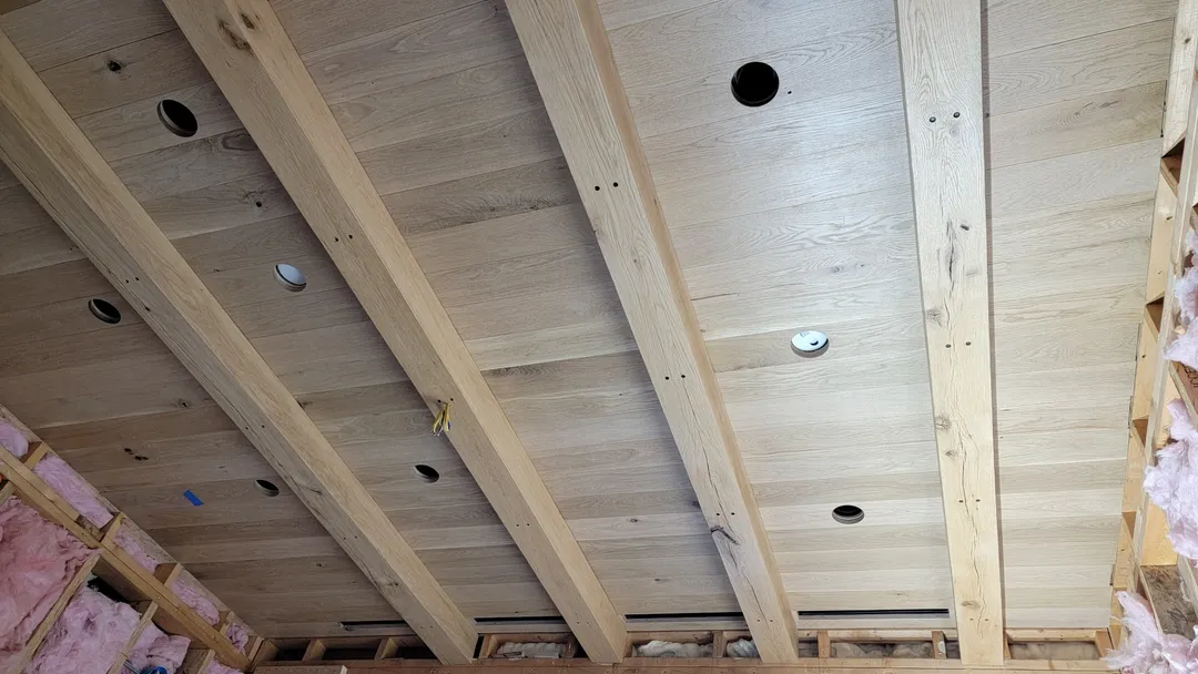 Wood ceiling panels fitted between exposed beams with integrated lighting openings.